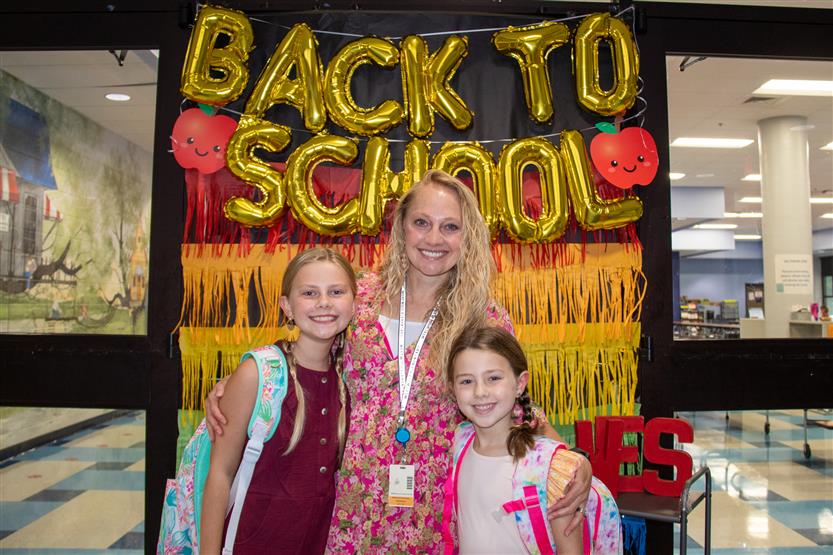 A family smiles in front of a Back-to-School sign